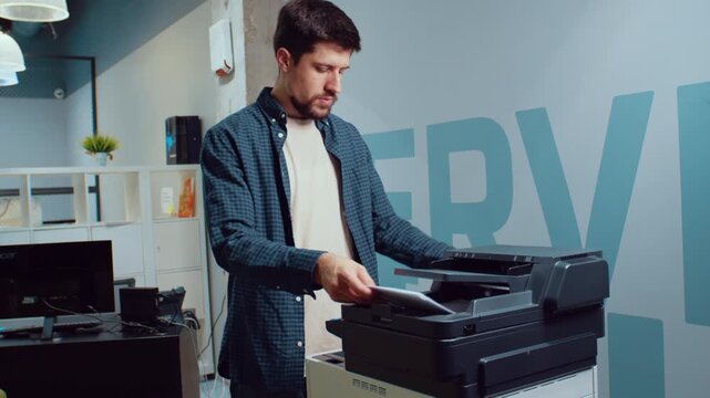 Man using a printer in an office setting to print documents during work hours
