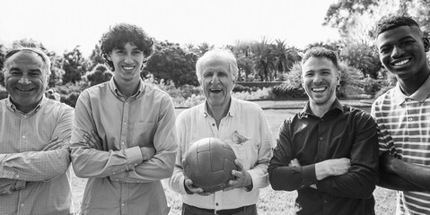 Multi generational men smiling in front of camera - Male multiracial group playing soccer with...