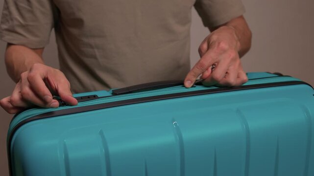 Traveler opening luggage, Close shot of hands unfastening suitcase zipper before travel, Detailed view of hands pulling zipper on vibrant teal travel case with anticipation