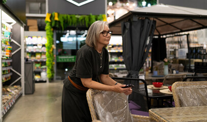 Fototapeta premium Middle-aged woman observes shoppers in a modern store setting while leaning on a chair around midday