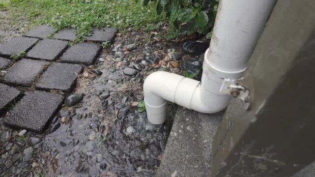 Rain, PVC Pipe, RainA white PVC downpipe connection overflows with stormwater during rainfall, creating pooling on the paved ground, illustrating urban drainage, water flow, and stormwater management 