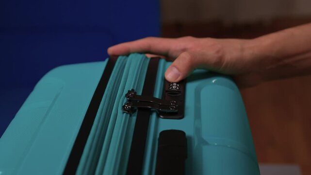 Secure suitcase with combo lock, Hands set combination on teal suitcase with textured surface, Closeup of hands adjusting numeric lock on stylish teal travel suitcase
