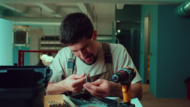 Man works on a small project using tools in a bright indoor area with a focus on precision tasks late in the day