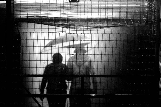 Pessoas usando capa de chuva e guarda chuva. 