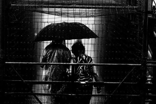 Pessoas usando capa de chuva e guarda chuva. 