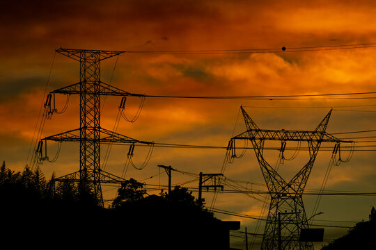 Uma torre de energia el&eacute;trica ou de transmiss&atilde;o uma estrutura met&aacute;lica com por-do-sol ao fundo. 