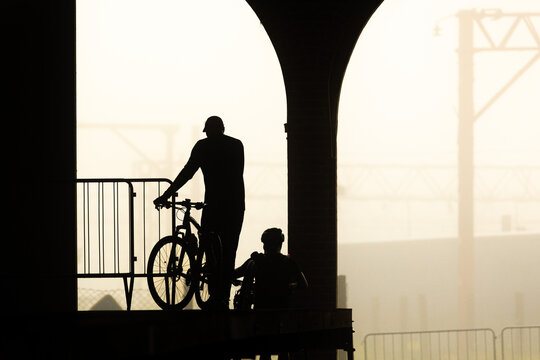 Silhueta de ciclistas em esta&ccedil;&atilde;o de trem. 