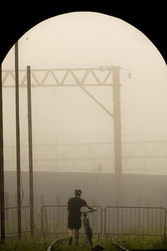Ciclistas atravessando linha f&eacute;rrea em meio a neblina.  