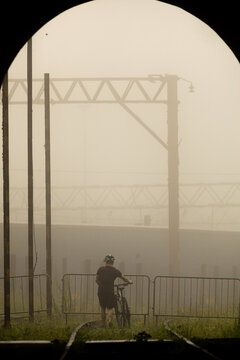 Ciclistas atravessando linha f&eacute;rrea em meio a neblina.  
