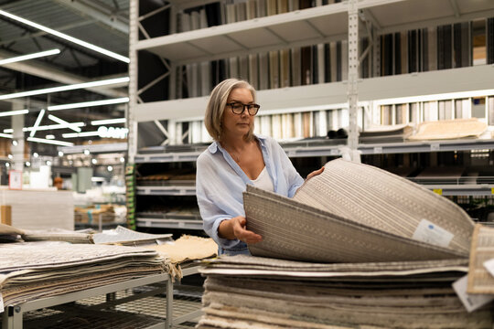 Woman selecting decorative rugs in a home decor store during the day
