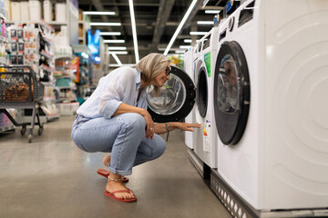Fototapeta premium Woman shopping for washing machines in a home appliance store during the daytime