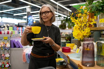 Woman shopping for dinnerware at home goods store in bright, organized atmosphere during the day