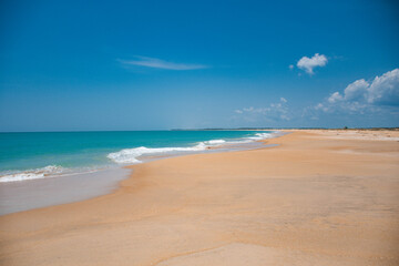 Fototapeta premium Soft Sandy Beach, Gentle Waves, and Charming Seaside Homes Beneath a Peaceful Cloudy Sky in Sri Lanka
