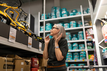 Senior woman shopping for household items in a bright store aisle filled with various products