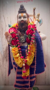 Lord Parshuram adorned with vibrant marigold garlands and traditional attire, holding a divine axe, symbolizing strength, righteousness, and warrior spirit in Hindu mythology inside a temple setting.
