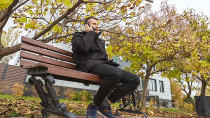 Fototapeta premium young man is looking at his phone, man in casual casual wear enjoying the autumn weather in street