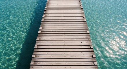 Obraz premium Wooden pier stretches over sparkling turquoise water, casting a shadow below