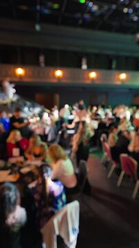 Participants engage with one another around tables beneath warm lights and melodic background tunes