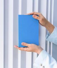 A woman's hands hold a blue notebook. Clean mockup background for marketing design. Copy space. Selective focus.