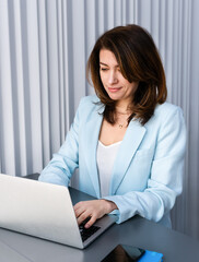 Portrait of a travel agency manager working on laptop in office. Female tourism consultant planning trips, customer service, booking management, professional travel business lifestyle.