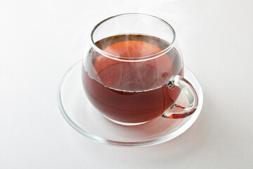 Hot infusion in a glass cup with saucer isolated