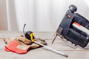 wooden workshop with a jigsaw (hacksaw), tape measure and construction gloves