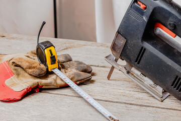 wooden workshop with a jigsaw (hacksaw), tape measure and construction gloves