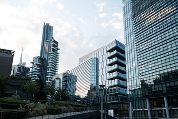 Naklejka premium Modern office buildings with glass facades against clear blue sky in Milan. Minimal urban architecture and corporate real estate concept.
