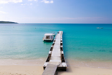Obraz premium Pier Extending into Turquoise Sea on a Tropical Island 南国の島のエメラルドブルーの海へ伸びる桟橋