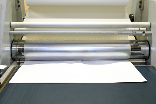 Work behind the laminator in the production shop of the printing house. Industrial laminator for film application.