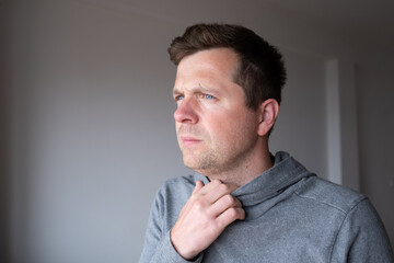 Fototapeta premium Pensive young man standing at home thinking about problems and making decisions