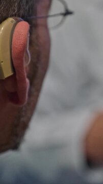 Detailed view of an elderly man with a hearing impairment using a modern digital bte hearing aid. Audiology and hearing loss concept