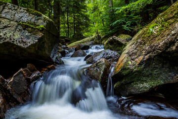 Obraz premium Fließendes sanftes Wasser in ruhigem Fluss mit Felsen
