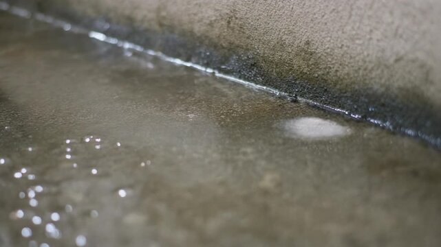Close-up of water droplet on concrete surface suggesting basement waterproofing and moisture.