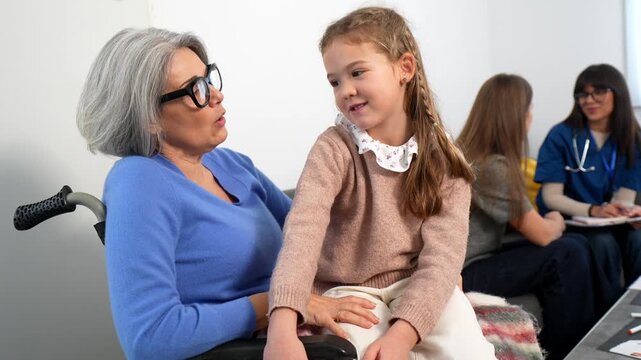 Granddaughter visiting grandmother in a wheelchair at nursing home