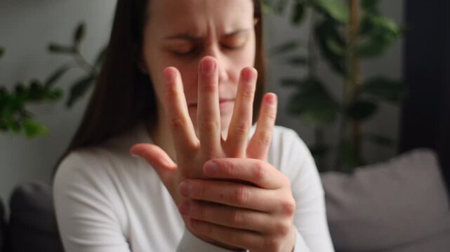 Close up of sad female massage hand with wrist pain, rheumatoid arthritis. Upset young woman suffer from numbing pain in hand, numbness fingertip, arthritis inflammation, peripheral neuropathies