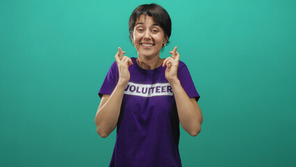 Woman with hands pressed together in a pleading prayer gesture wearing a volunteer t shirt against...