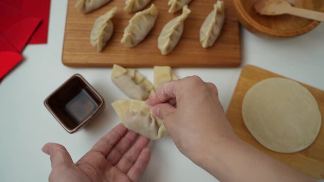 Hands preparing traditional Chinese dumplings with wrappers and filling on a clean table.Asian home cooking process, food preparation concept for Chinese New Year, family cooking,and homemade cuisine.