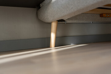 Obraz premium Bright sunlight shadows on wood floor by a modern grey bed