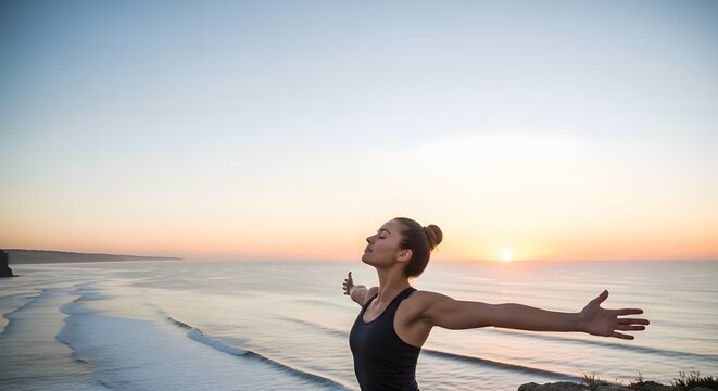 A woman stretches her arms wide while standing by the sea at sunrise, embracing freedom, positivity, and fresh ocean air.