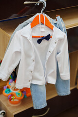 Cute outfit for a child hanging on a clothes hanger in a playroom