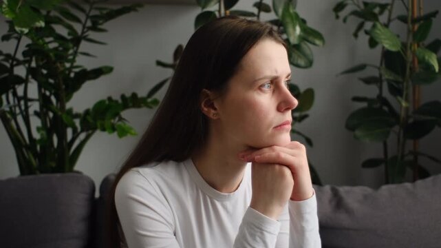 Unhappy anxiety young caucasian woman sitting alone on couch at home, hurt heartbroken female in depression feel desperate and anxious having psychological troubles
