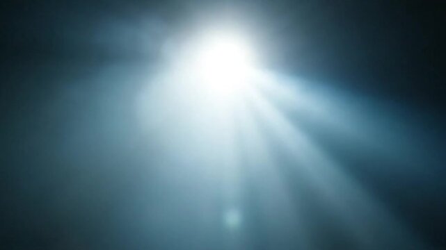 Bright light shining through darkness in stages. Bright light source emerging and expanding with lens flare effect.