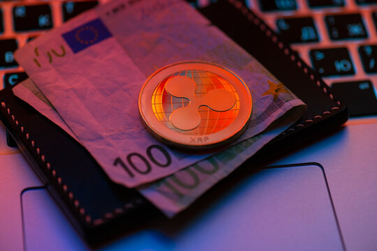 Kyiv, Ukraine - February 06, 2026 Close-up Ripple XRP cryptocurrency token on computer keyboard with leather wallet under purple neon lighting, The image conveys digital money and blockchain technolog