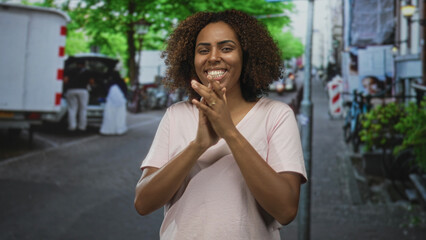 Fototapeta premium Woman clapping hands on a city street with a joyful smile and raised palms in applause; joy gratitude celebration.