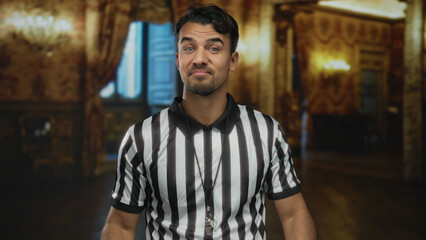 Obraz premium Young hispanic man wearing referee uniform making uncertain gesture inside museum with ornate decor suggesting confusion or doubt amid elegant setting.