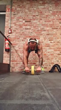 Man at the gym training abs with a wheel