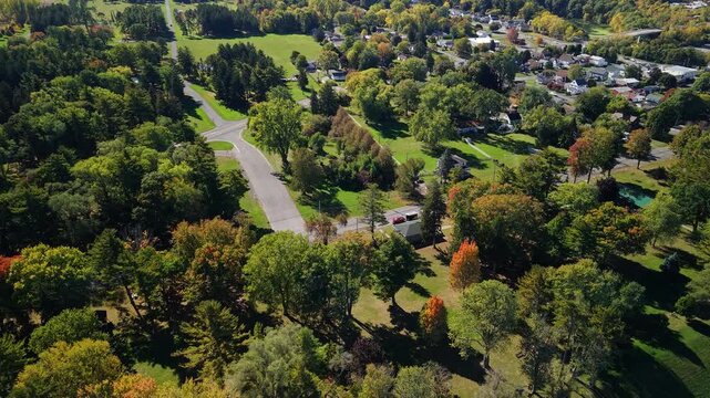 Aerial view of green suburban area with parkland, trees, residential streets, and scattered houses, showing low density urban planning, transport access, and everyday American suburb environment