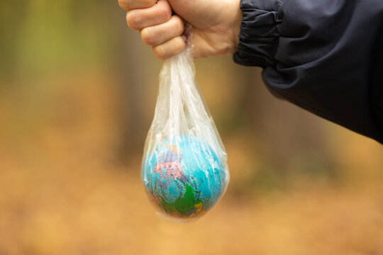 Woman person hand holding Earth globe in a plastic trash bag symbolizes the environmental challenges Earth and pollution crisis.