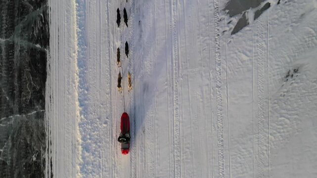 Top-down aerial view of orthodox christian priests leading a dog sled team across a frozen landscape